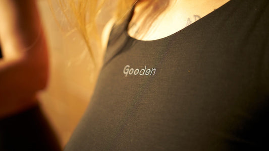 Woman wearing a GOODEN Crop Top and showing the brand logo for sustainable clothing.